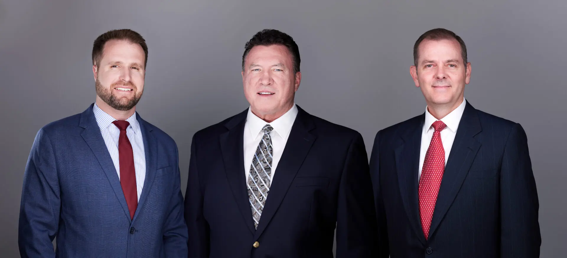 Three businessmen in suits smiling.